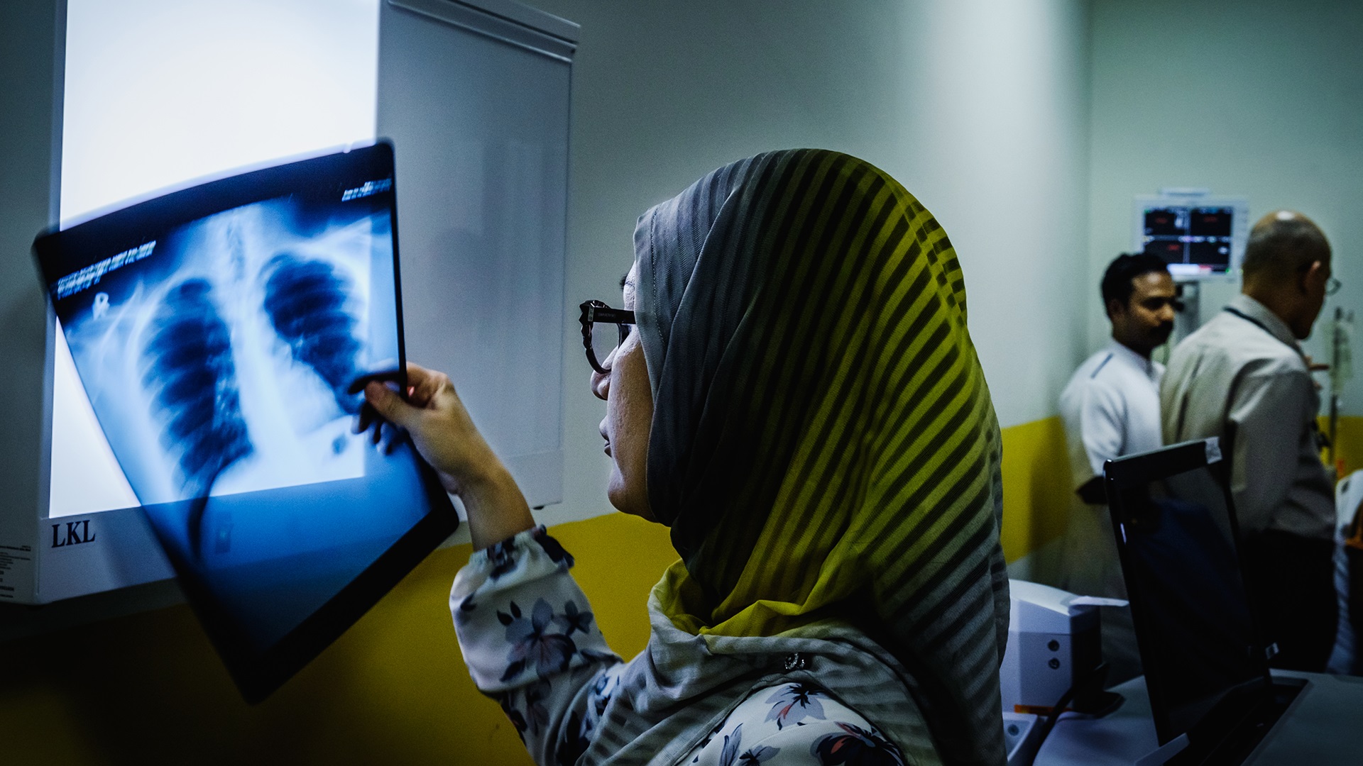 Photo of a woman holding an X-ray in her hand in an exam room at a hospital in Bandar Seri Begawan, Brunei Darussalam.